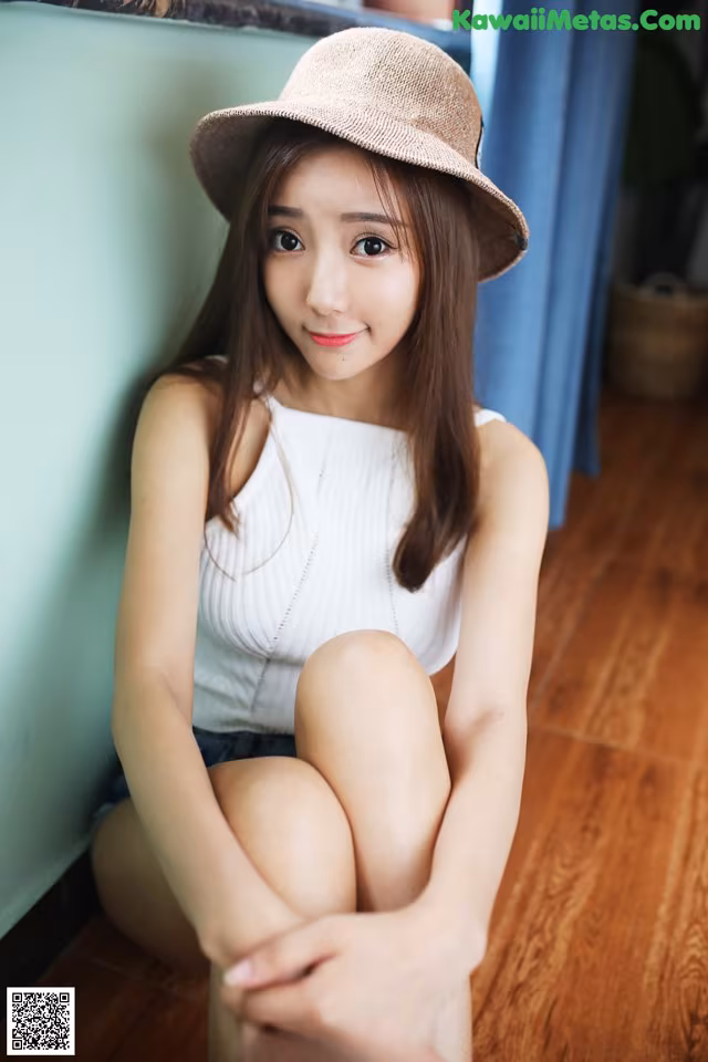 A woman sitting on the floor wearing a hat.