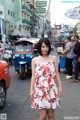 A woman in a floral dress standing in the middle of a busy street.