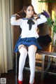 A woman in a school uniform sitting on a table.