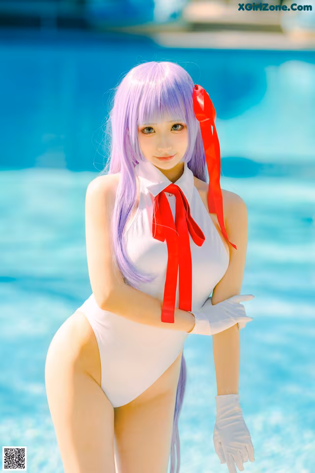 A woman in a white bathing suit standing next to a pool.