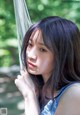 A young woman leaning against a hammock in the woods.