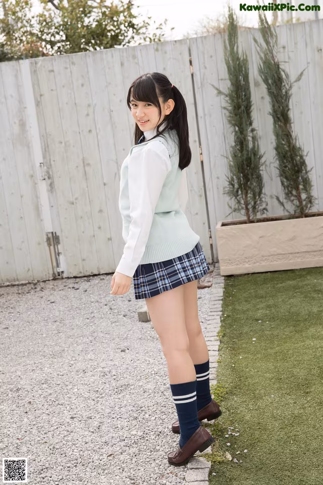 A young woman in a school uniform is posing for the camera.