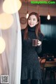 A woman in a black sweater holding a cup of coffee.