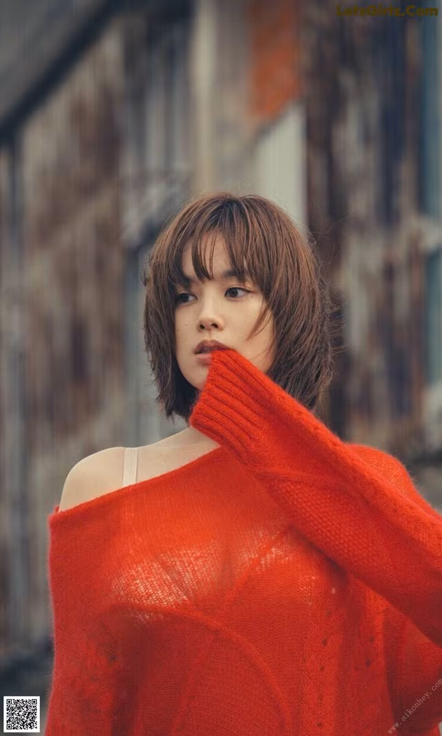 A woman in a red sweater is posing for a picture.