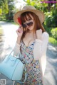 A woman wearing a straw hat and sunglasses holding a blue bag.