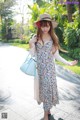 A woman in a dress and hat is walking down a sidewalk.