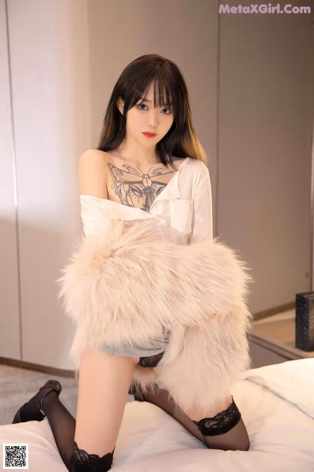 A woman sitting on top of a bed wearing a fur coat.