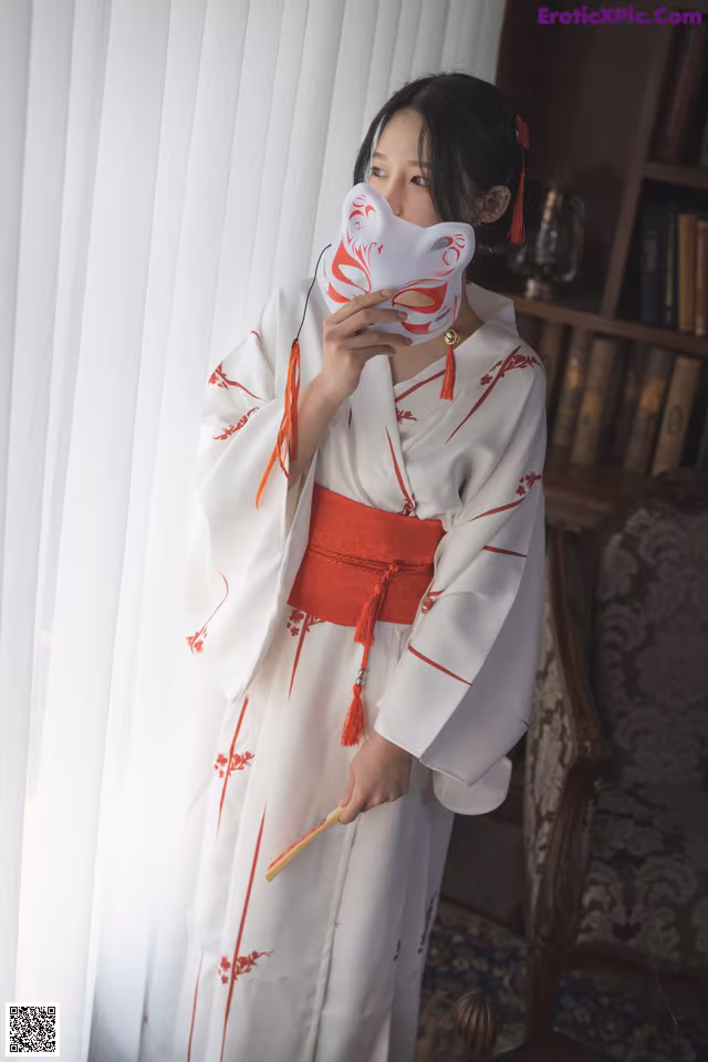 A woman in a white and red kimono holding a fan.