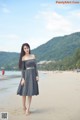 A woman in a gray dress standing on a beach.