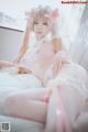 A woman in a white lingerie sitting on a bed.