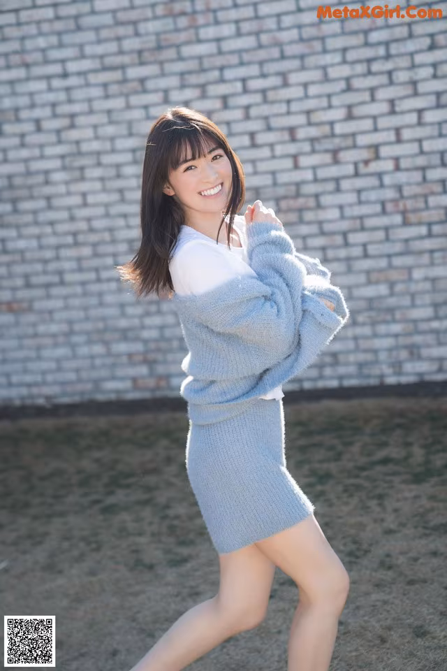 A woman in a blue sweater and skirt posing for a picture.