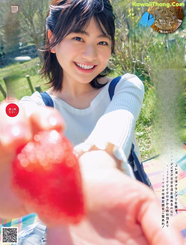 A woman holding a strawberry in her hand. 