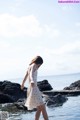 A woman in a white dress standing in the water.