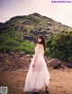 A woman in a white dress standing on a dirt road.