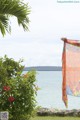 A person holding up a colorful scarf in front of the ocean.