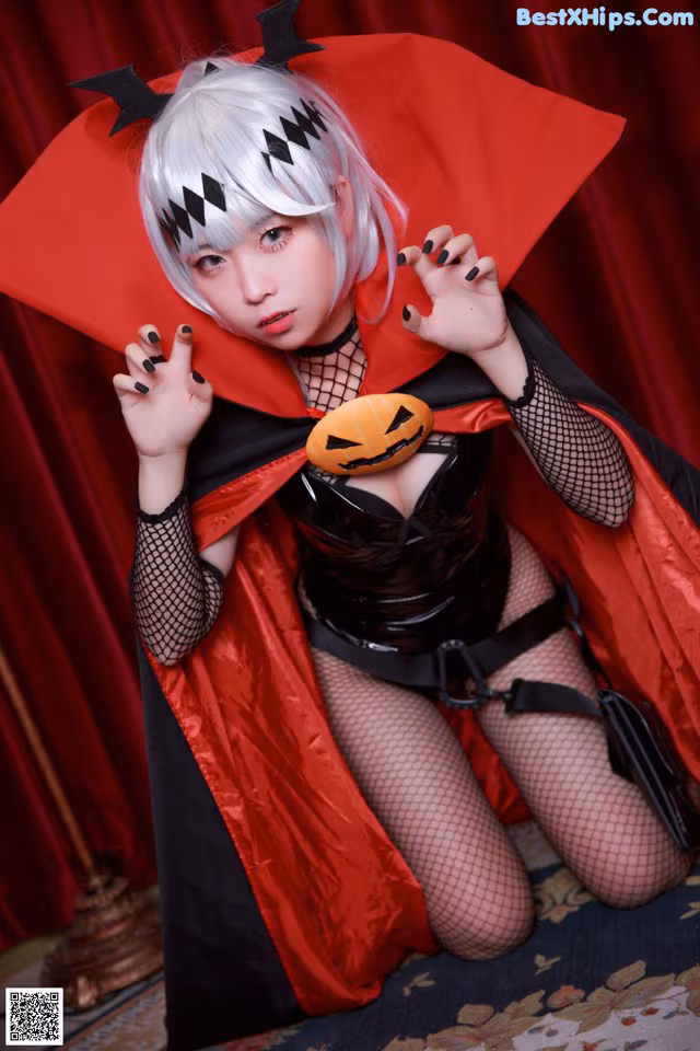 A woman dressed as a vampire holding a pumpkin.