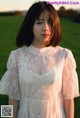 A woman in a white dress standing in a field.