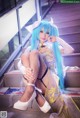 A woman with long blue hair sitting on some stairs.