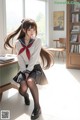 A woman in a school uniform sitting on a desk.