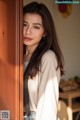 A woman leaning against a wooden door in a room.