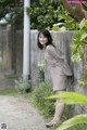 A woman leaning against a wall in a garden.