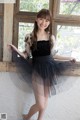 A woman in a black dress posing in front of a window.