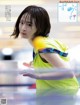 A woman in a yellow shirt is playing ping pong.