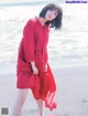 A woman in a red dress standing on a beach.